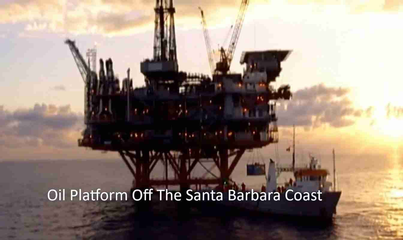 Offshore oil platform on stilts with a supply vessel nearby, silhouetted at sunset off the Santa Barbara Coast.