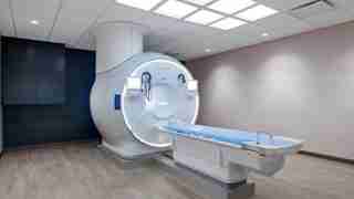 MRI scanner with patient table extending from the circular bore in a clinical room