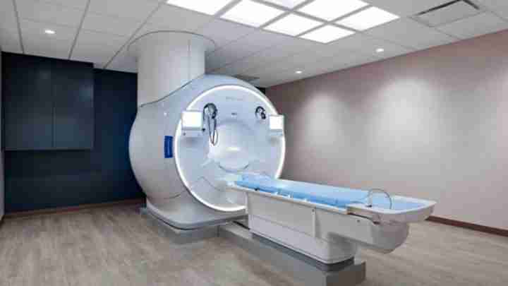 MRI scanner with patient table extending from the circular bore in a clinical room