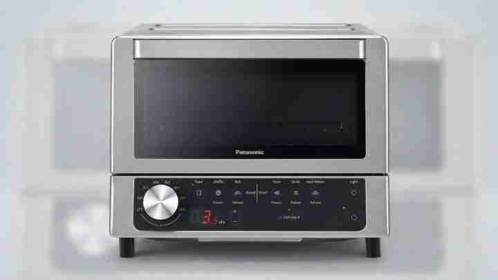 Stainless steel countertop oven with a digital control panel and round dial on the left side.