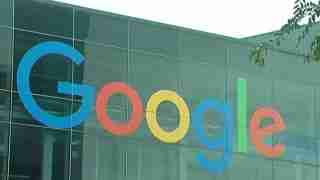 Google logo letters in blue, red, yellow, and green on a glass building facade.
