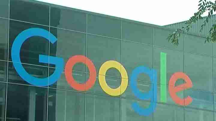 Google logo letters in blue, red, yellow, and green on a glass building facade.