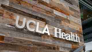 UCHealth sign mounted on a rustic wooden wall exterior outside a building.