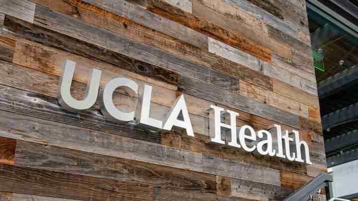 UCHealth sign mounted on a rustic wooden wall exterior outside a building.